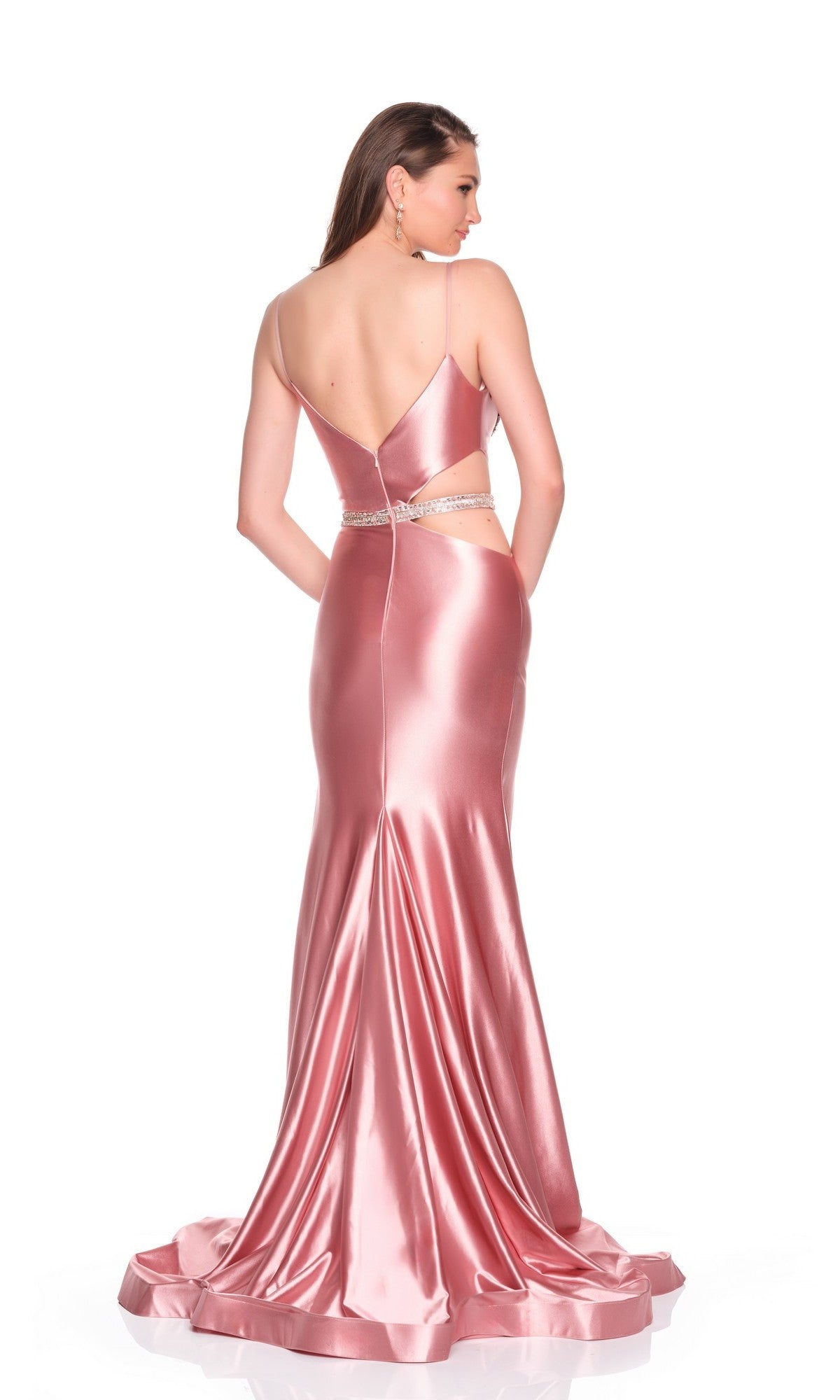 A woman models the Dave and Johnny 12911 long prom dress: a shiny satin pink gown with an open back, fitted waist, thin straps, hot-stone embellished bodice, floor-length train, and thigh-high slit against a white background.